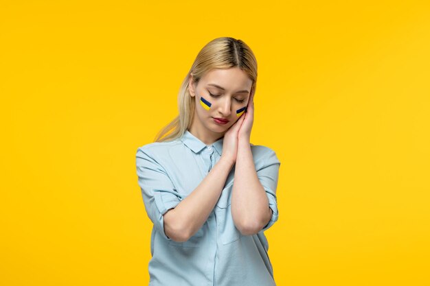 Conflicto ucraniano ruso linda chica fondo amarillo con bandera ucraniana en las mejillas tranquilas