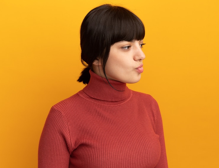 Foto gratuito confundida joven morena caucásica mira al lado aislado en la pared naranja con espacio de copia