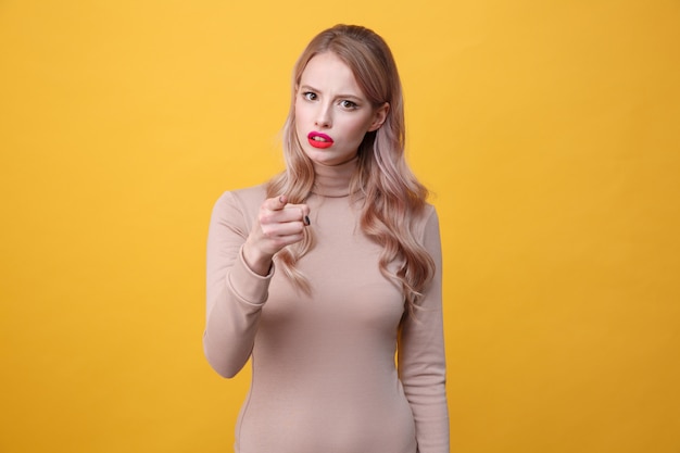 Confundida jovencita rubia con labios de maquillaje brillante señalando