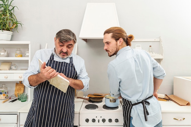 Confundido padre e hijo mirando en un libro de cocina