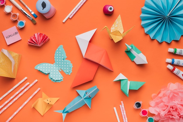 Conjunto de arte de papel de origami; Cepillo de pintura; Acuarela y paja sobre fondo naranja.