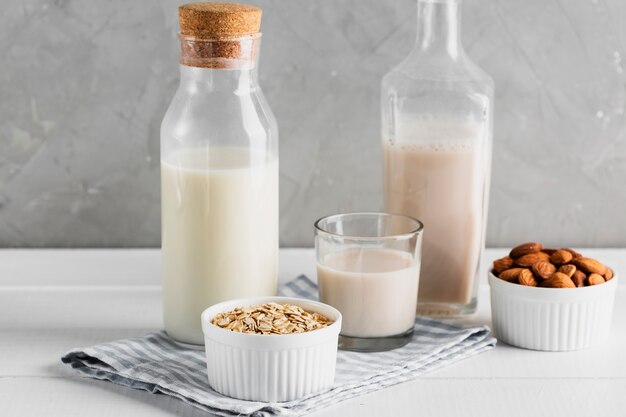 Conjunto de botellas de leche y vasos con avena y almendras