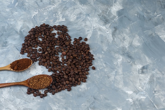 Conjunto de café instantáneo y harina de café en cucharas de madera y granos de café sobre un fondo de mármol azul claro. de cerca.