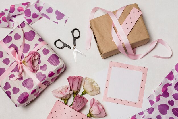 Conjunto de cajas de regalo cerca de flores, papeles y tijeras.