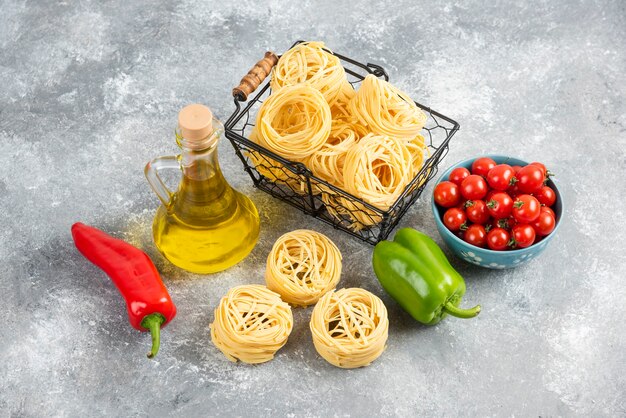 Conjunto de champiñones, aceite de oliva virgen extra, pastas, tomates cherry y guindillas sobre una pieza de mármol.