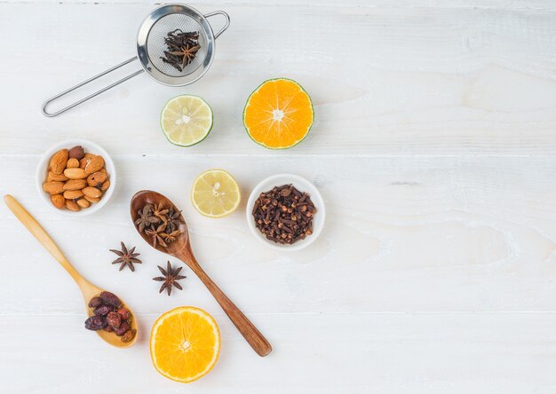 Conjunto de clavo y frutas cítricas y almendras en un recipiente blanco sobre una superficie blanca