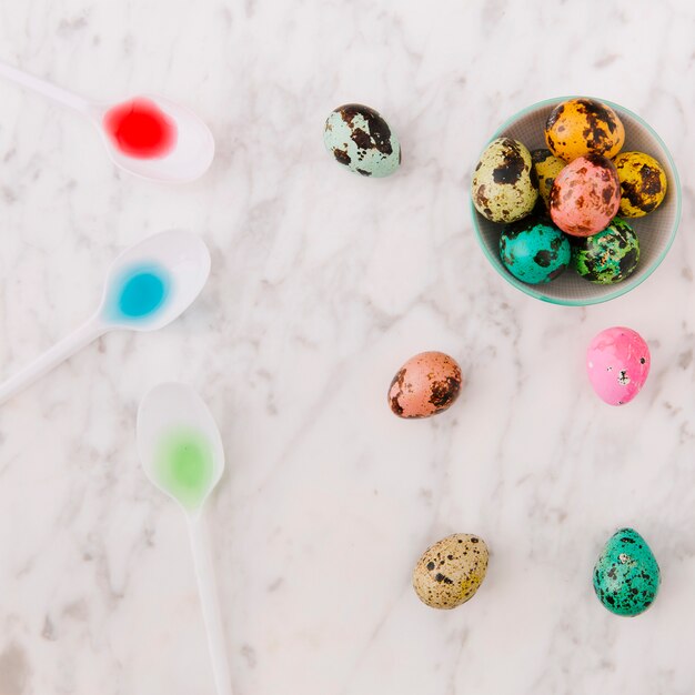 Conjunto de codornices coloridos huevos de Pascua en un tazón cerca de una cuchara con tintes