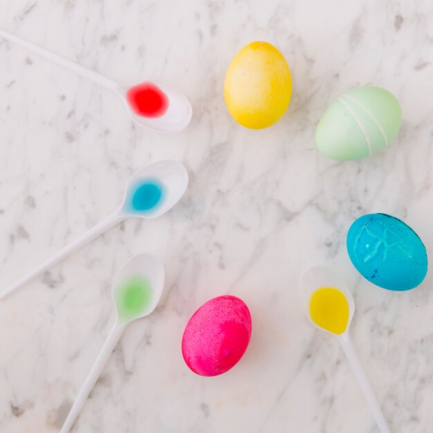 Conjunto de coloridos huevos de Pascua en un tazón cerca de una cuchara con tintes