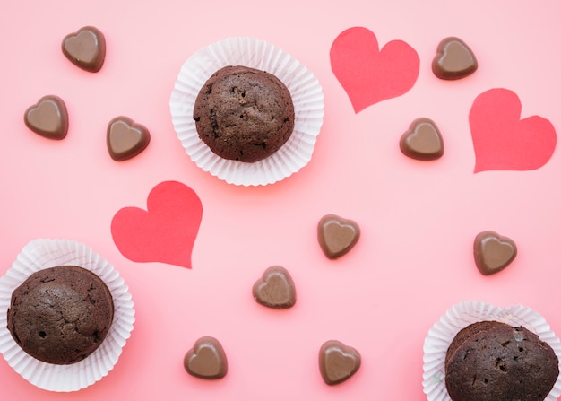 Conjunto de corazones de chocolate dulce cerca de muffins y tarjetas de San Valentín