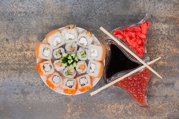 Conjunto de delicioso sushi con palillos y jengibre en superficie de mármol