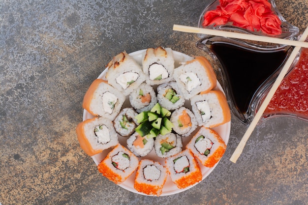 Conjunto de delicioso sushi con palillos y jengibre en superficie de mármol