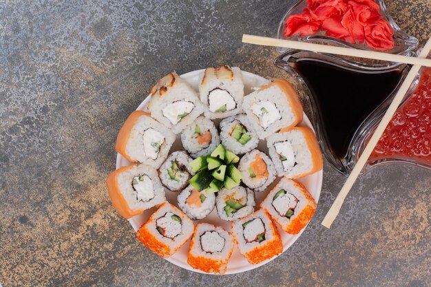 Conjunto de delicioso sushi con palillos y jengibre en superficie de mármol