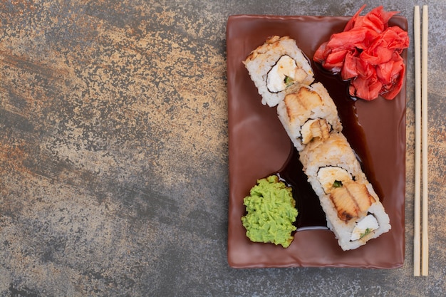 Conjunto de delicioso sushi con palillos y jengibre en superficie de mármol