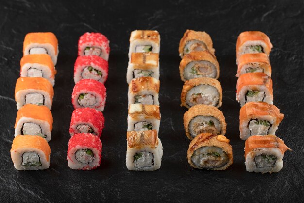 Conjunto de deliciosos rollos de sushi tradicionales en superficie negra