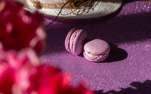 Un conjunto de dos macarrones morados en el fondo de flores de fondo morado brillante