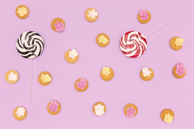 Foto gratuito conjunto de dulces y piruletas sobre fondo morado