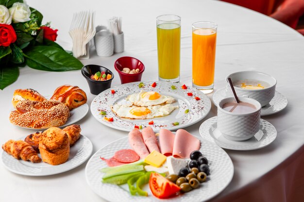 Conjunto de ensalada, huevos fritos y pasteles y delicioso desayuno en una mesa sobre un fondo blanco. Vista de ángulo alto.