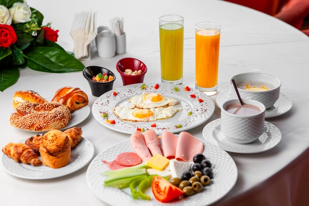 Conjunto de ensalada, huevos fritos y pasteles y delicioso desayuno en una mesa sobre un fondo blanco. Vista de ángulo alto.