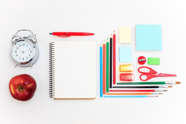 Conjunto escolar con cuadernos, lápices, pincel, tijeras y manzana en blanco