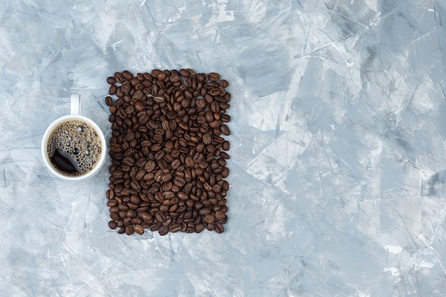 Conjunto de granos de café y café en una taza sobre un fondo de mármol azul. vista superior.