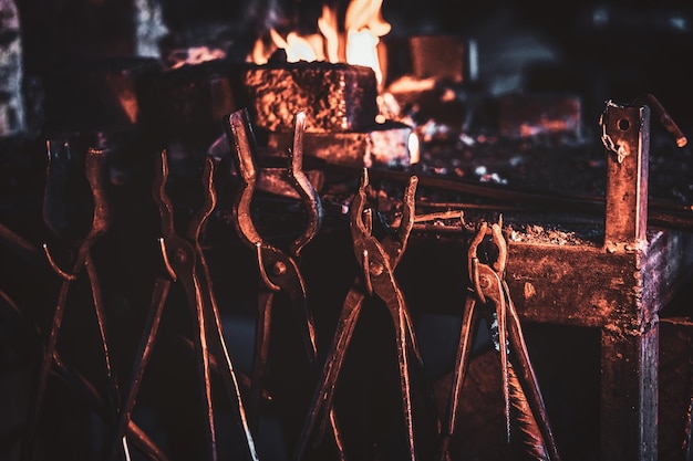 Conjunto de herramientas con brillo de fuego en el taller de herrería oscura.