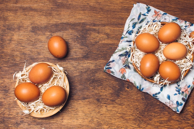 Foto gratuita conjunto de huevos de gallina en cuencos sobre material floreado a bordo