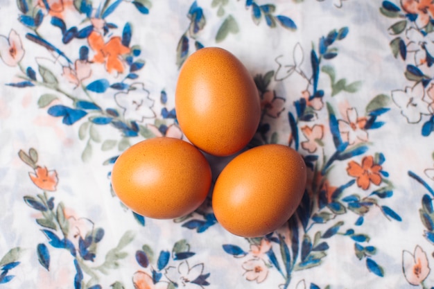 Foto gratuita conjunto de huevos de gallina sobre material floreado.