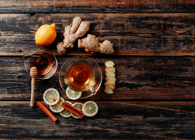 Conjunto de jengibre, miel, canela seca, té y verde y limón sobre fondo de madera oscura. vista superior. espacio para texto