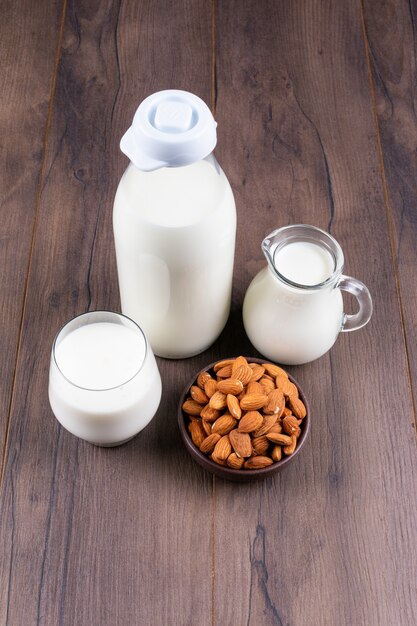 Conjunto de leche y almendras sobre una mesa oscura y de madera. Vista de ángulo alto.