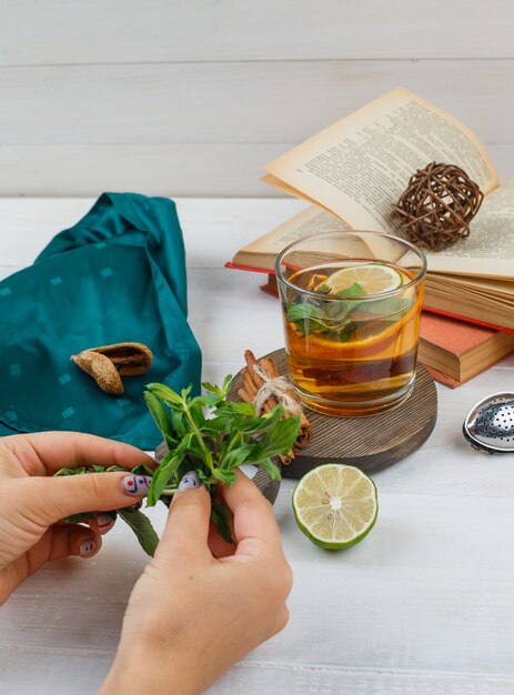 Conjunto de libros, limón, menta y bufanda verde y té de hierbas y canela sobre una tabla de madera