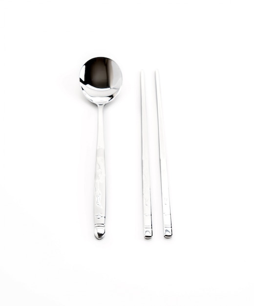 Un conjunto de palillos chinos de metal plano y cuchara