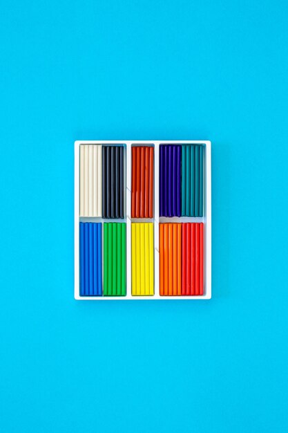 Conjunto de palos de plasticina de colores aislados en un fondo azul vista superior