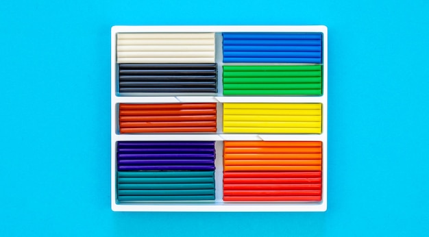 Foto gratuita conjunto de palos de plastilina de colores aislados en un fondo azul de arco iris de modelado pieza de arcilla para niños juego y creatividad