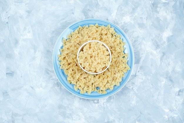 Conjunto de pasta farfalle en tazón y plato sobre un fondo de yeso. vista superior.