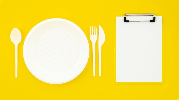 Foto gratuita conjunto de plato blanco y portapapeles sobre fondo amarillo