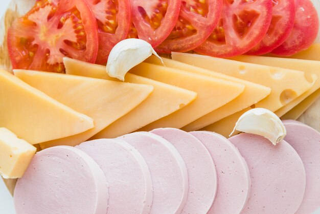 Conjunto de queso fresco junto a tomates y carne de almuerzo.