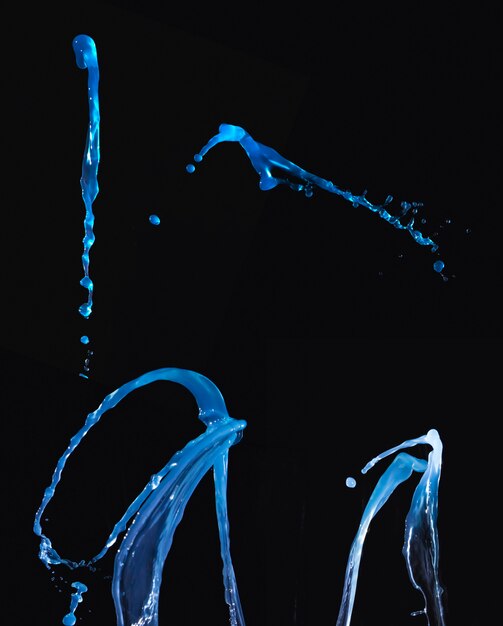 Conjunto de salpicaduras de líquido azul sobre fondo oscuro