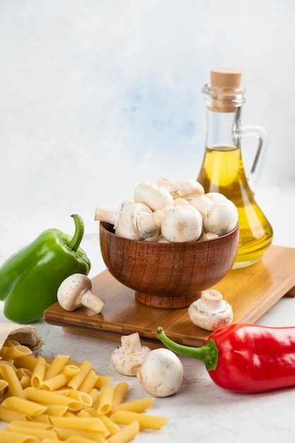 Conjunto de setas blancas, pastas, guindillas y aceite de oliva virgen extra sobre el mármol.