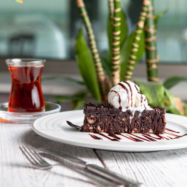 Conjunto de té, plantas y postre en un plato sobre un fondo blanco de madera. vista lateral.