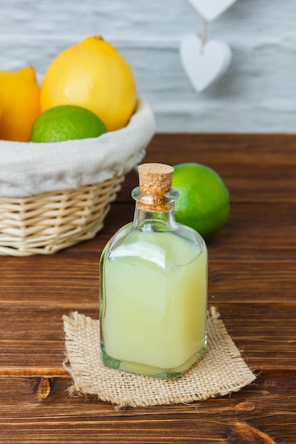 Conjunto de un trozo de tela blanca y limón y jugo en una canasta sobre una superficie de madera. vista de ángulo alto.