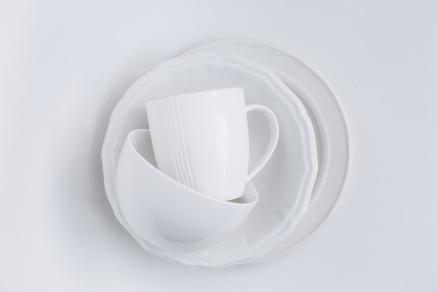 conjunto de utensilios blancos en una pila de tres platos diferentes y una taza