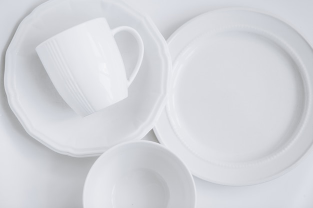 conjunto de utensilios blancos de tres platos diferentes y una taza en un plato