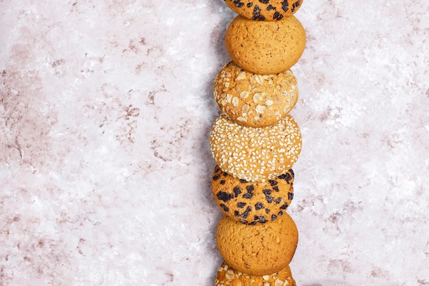 Conjunto de varias galletas de estilo americano sobre un fondo de hormigón ligero. Galletas de mantequilla con confeti, semillas de sésamo, mantequilla de maní, avena y galletas de chispas de chocolate.