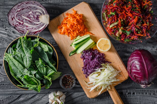 Conjunto de verduras y ensalada de verduras en cuencos en un paño de picnic y fondo de madera oscura. vista superior. espacio para texto