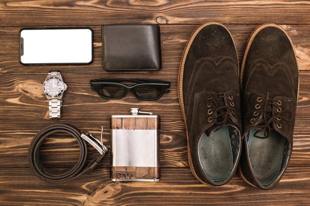 Conjunto de zapatos masculinos cerca de smartphone y accesorios.