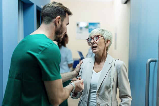 Conmocionada anciana recibiendo malas noticias de un cirujano en el hospital