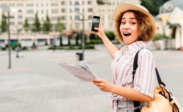 Conmocionada mujer sosteniendo un mapa y un teléfono