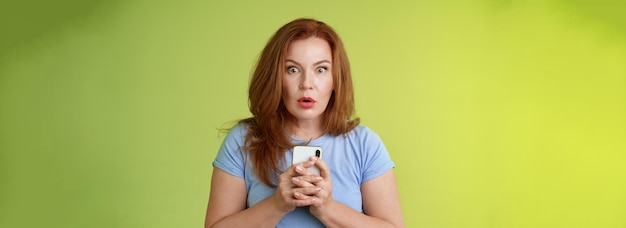 Foto gratuita conmocionada, sin palabras, impresionada, pelirroja europea de mediana edad, mujer con los labios plegados, asombrada, mirando fijamente a la cámara.