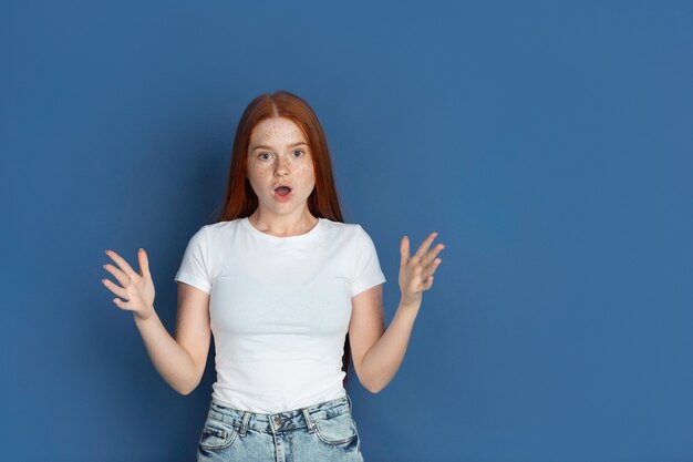 Conmocionado asombrado retrato de jovencitas caucásicas en pared azul