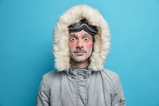 Conmocionado hombre adulto congelado mira fijamente tiene ojos aparecieron cara roja congelada durante el clima helado